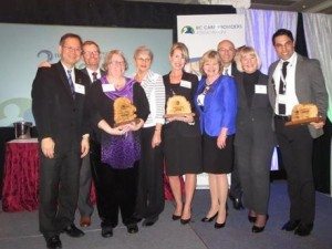 Award Recipients, Hon. Terry Lake, MLAs, & CEO Daniel Fontaine gather on stage for a group photo at 2015 BC Care Awards